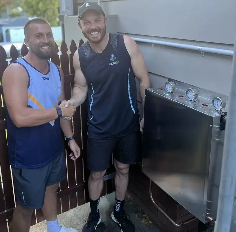 Adam from Central Coast Water Filtration shaking hands with a happy customer beside their new system